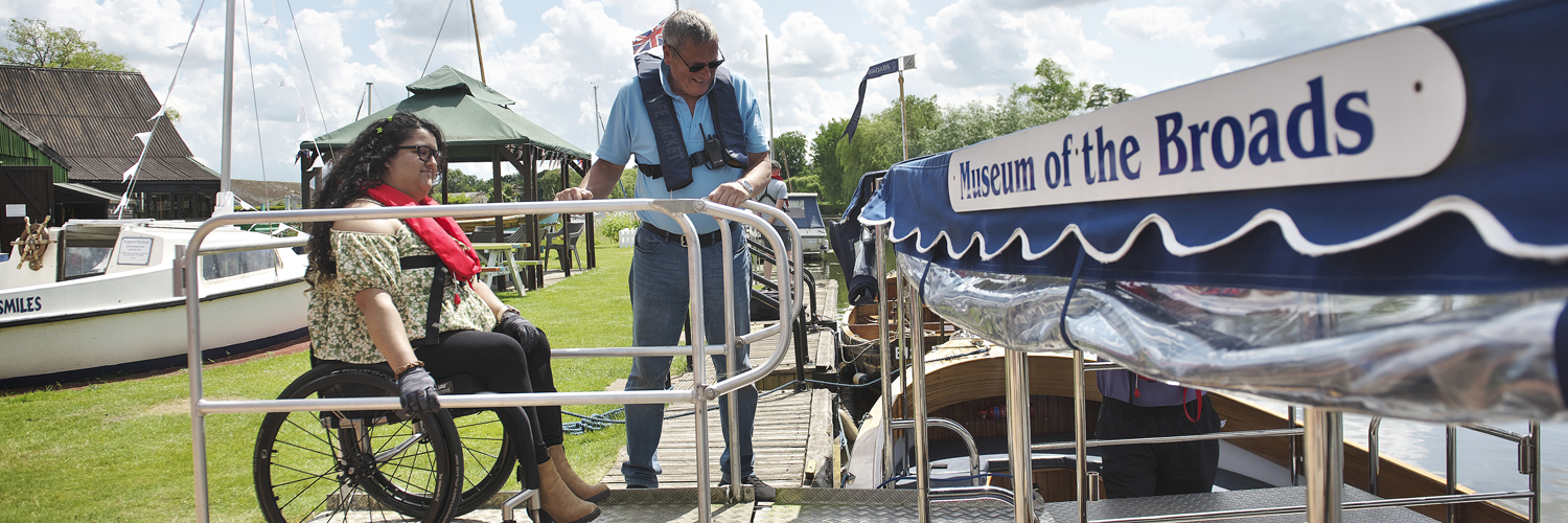 a female wheelchair user boarding an accessible boat trip at the museum of the broads