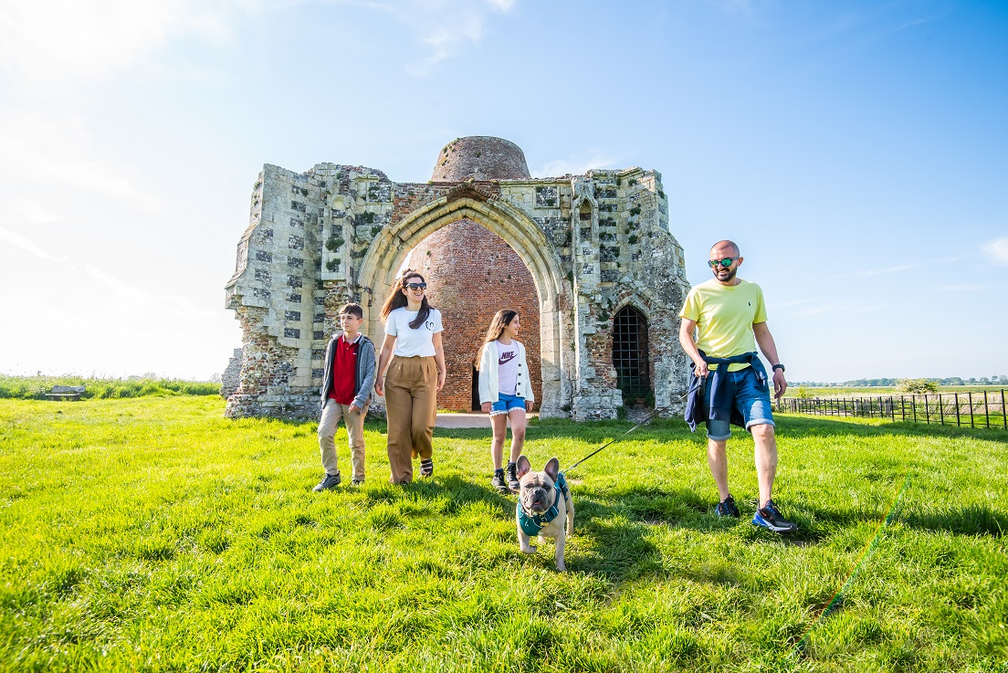 A family walking their dog at St Benet’s Abbey on a sunny day.